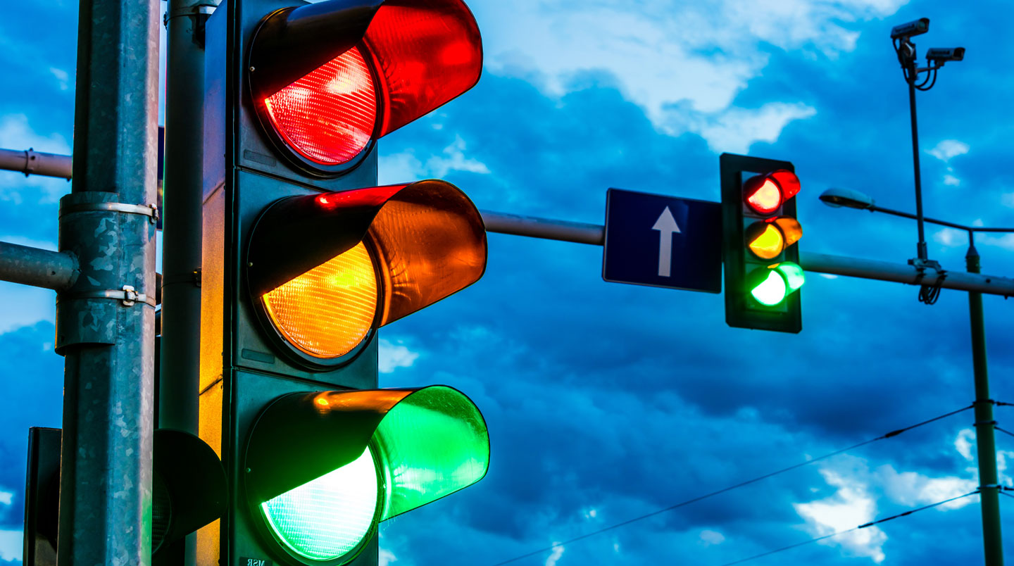 Feu tricolore LED moderne connecté avec boîtier de contrôle intelligent et interface numérique, technicien municipal accédant au système de pilotage en temps réel sur une intersection urbaine française